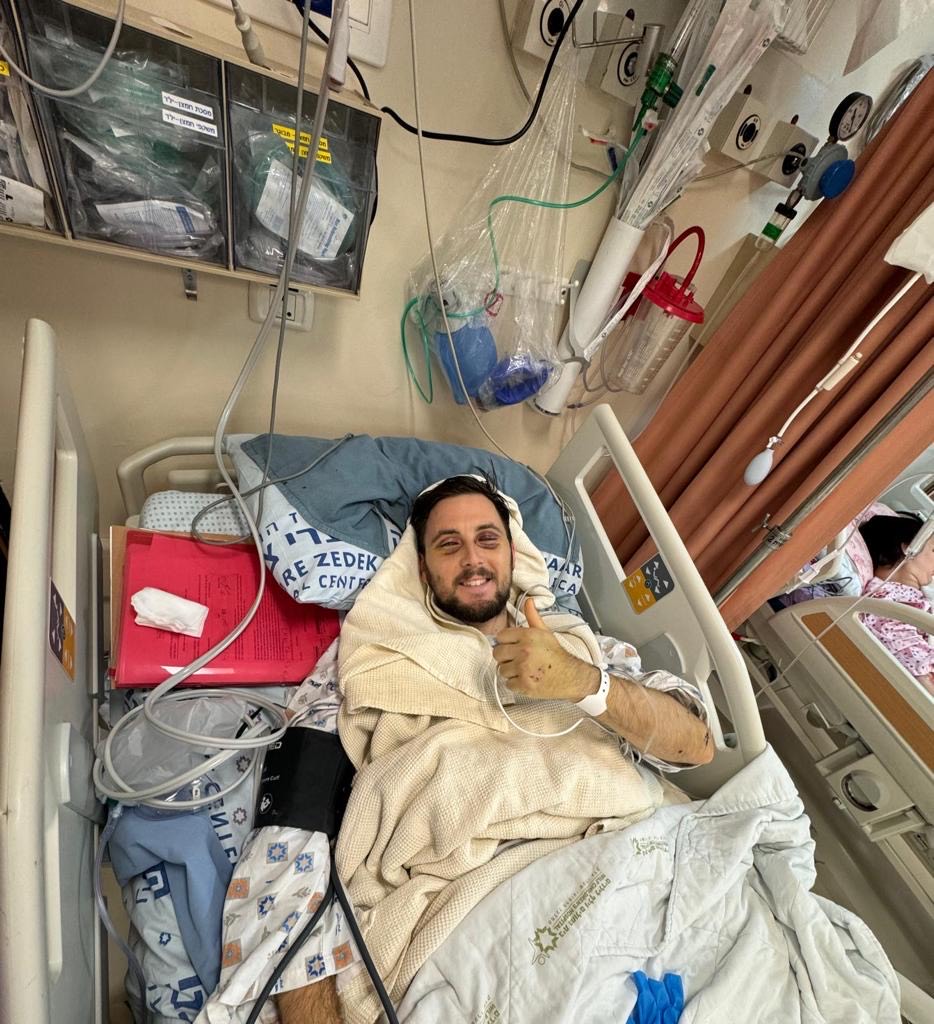 Football program participant recovering in hospital, giving a thumbs up